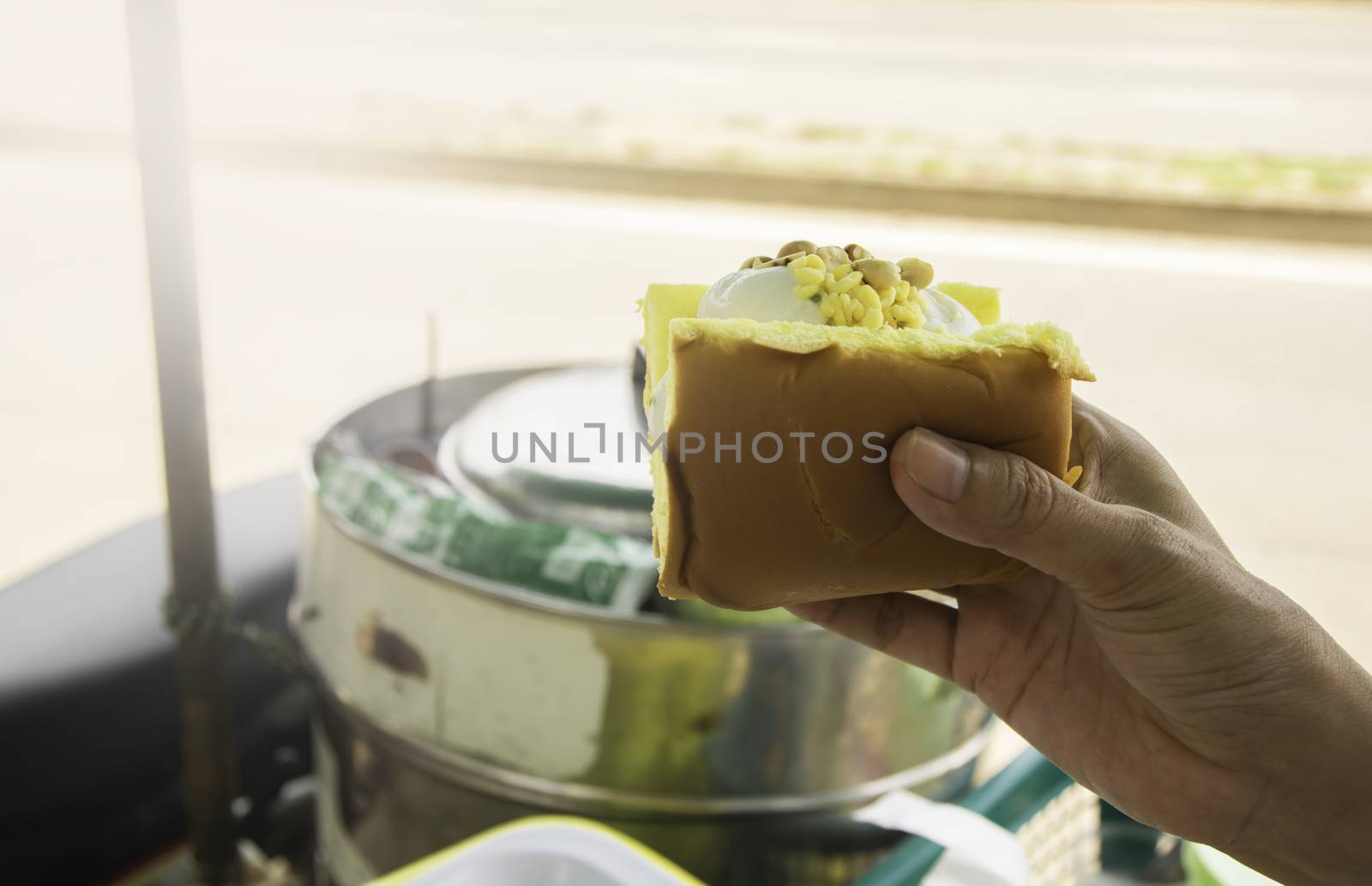 Female hand holding and buying ice cream in bread with bean on top