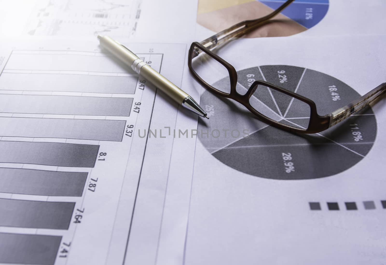 Pen with glasses on document for analyzing financial data and counting.