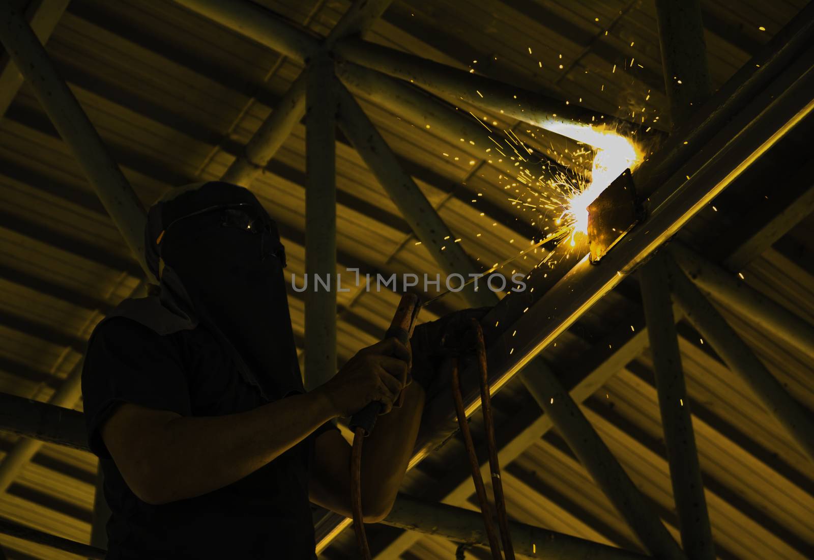 Industrial Worker at the factory steel welding under the roof.