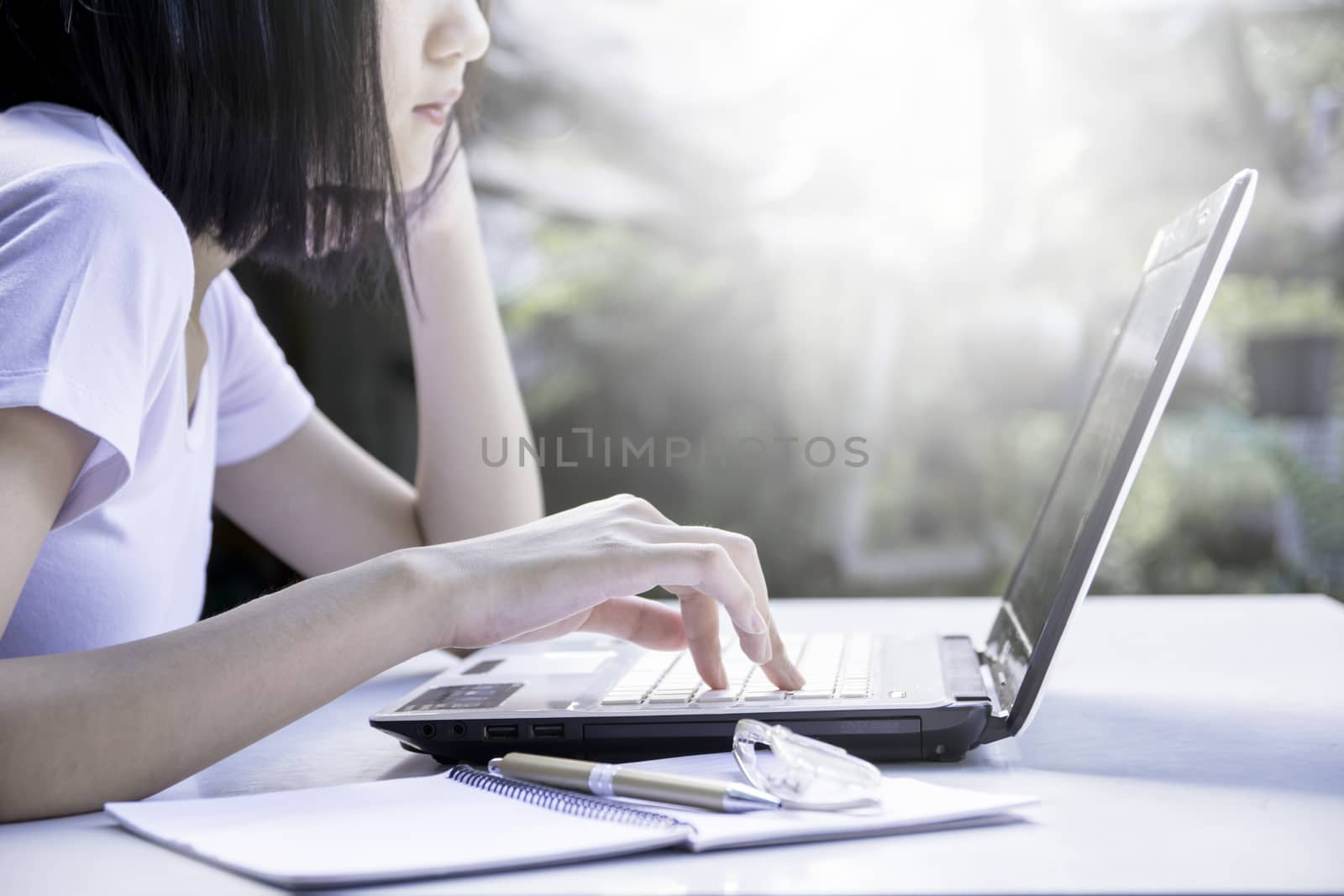 Young business woman working on laptop computer while sitting on white table