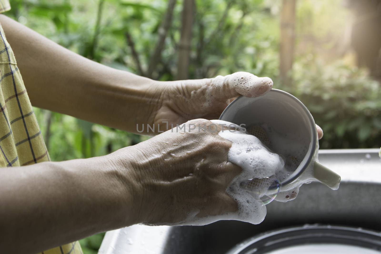 Close up hands of woman washing dishes in the kitchen. by kirisa99