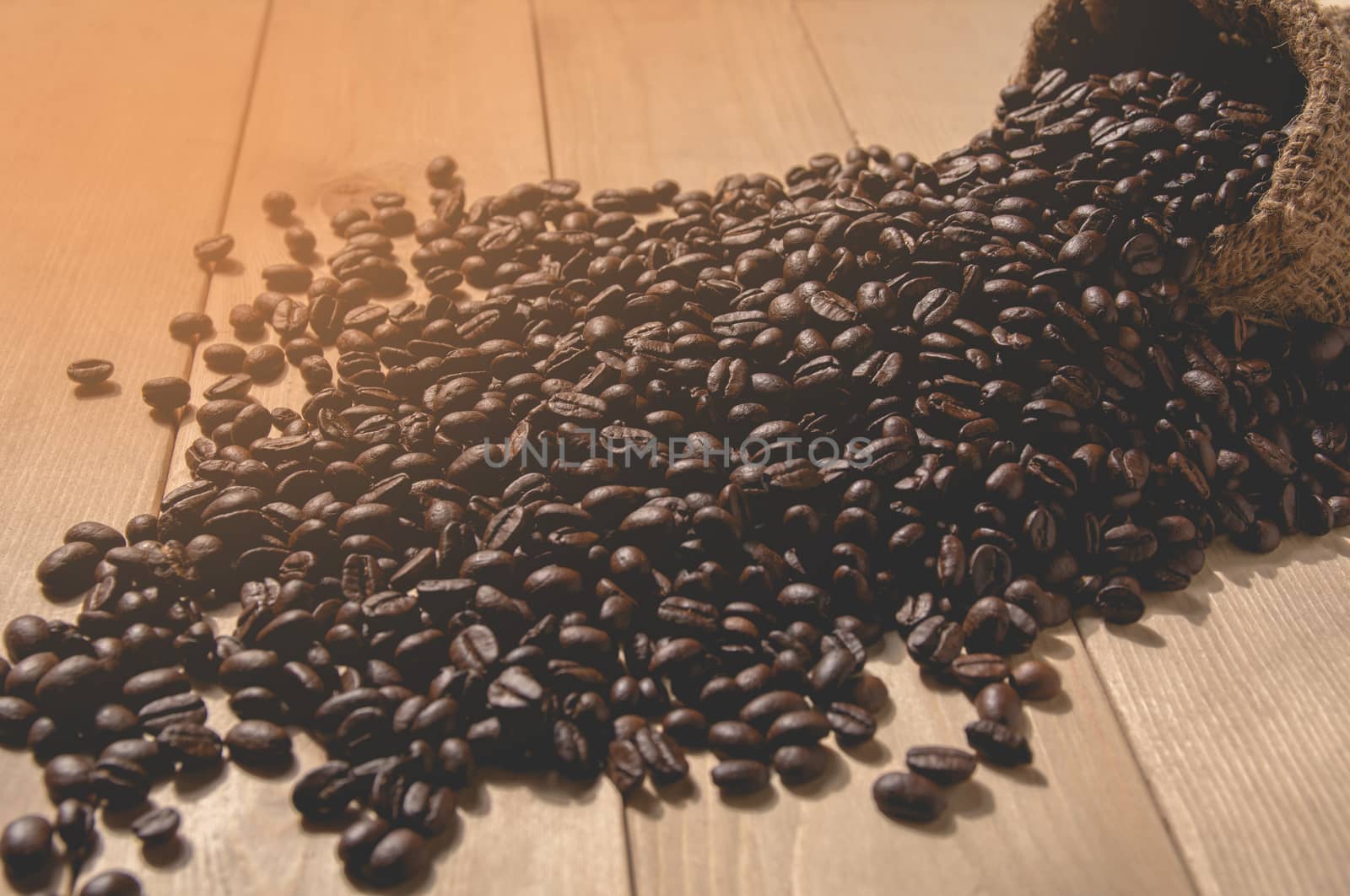 Coffee beans with sack bag on wooden table background.