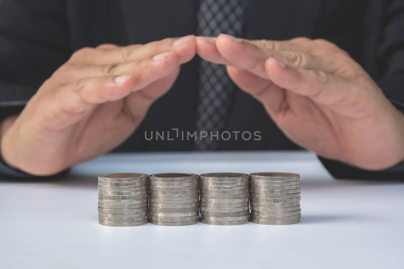 stack coins with hand of businessman cover stack coins. Financial and saving concept.