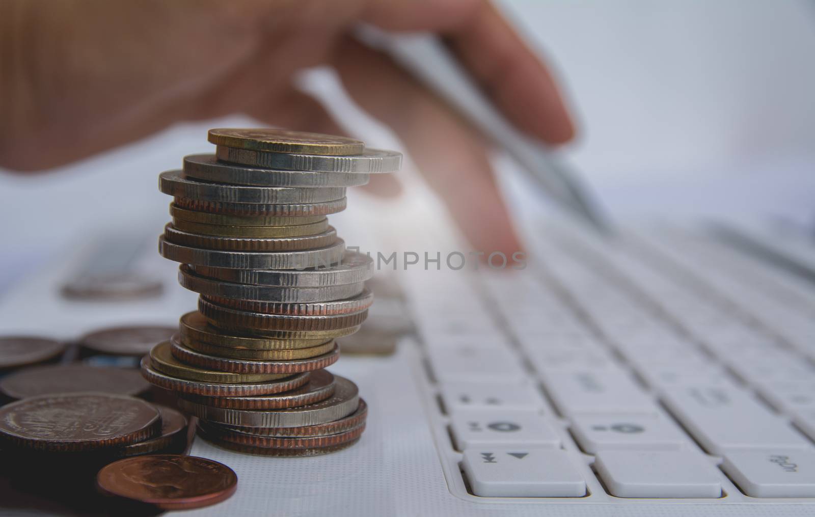 stack coins on white laptop and finger press button on keyboard. by kirisa99