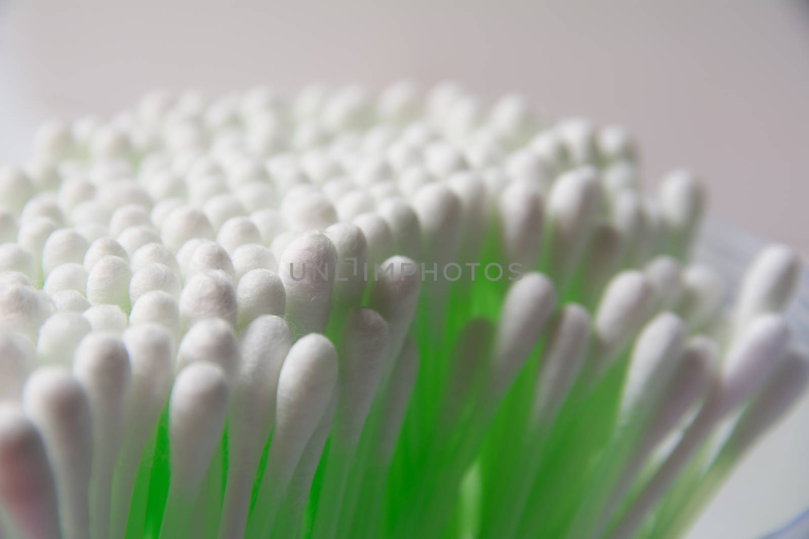 Green cotton swab bud over the grey background. Group of green plastic cotton swabs.