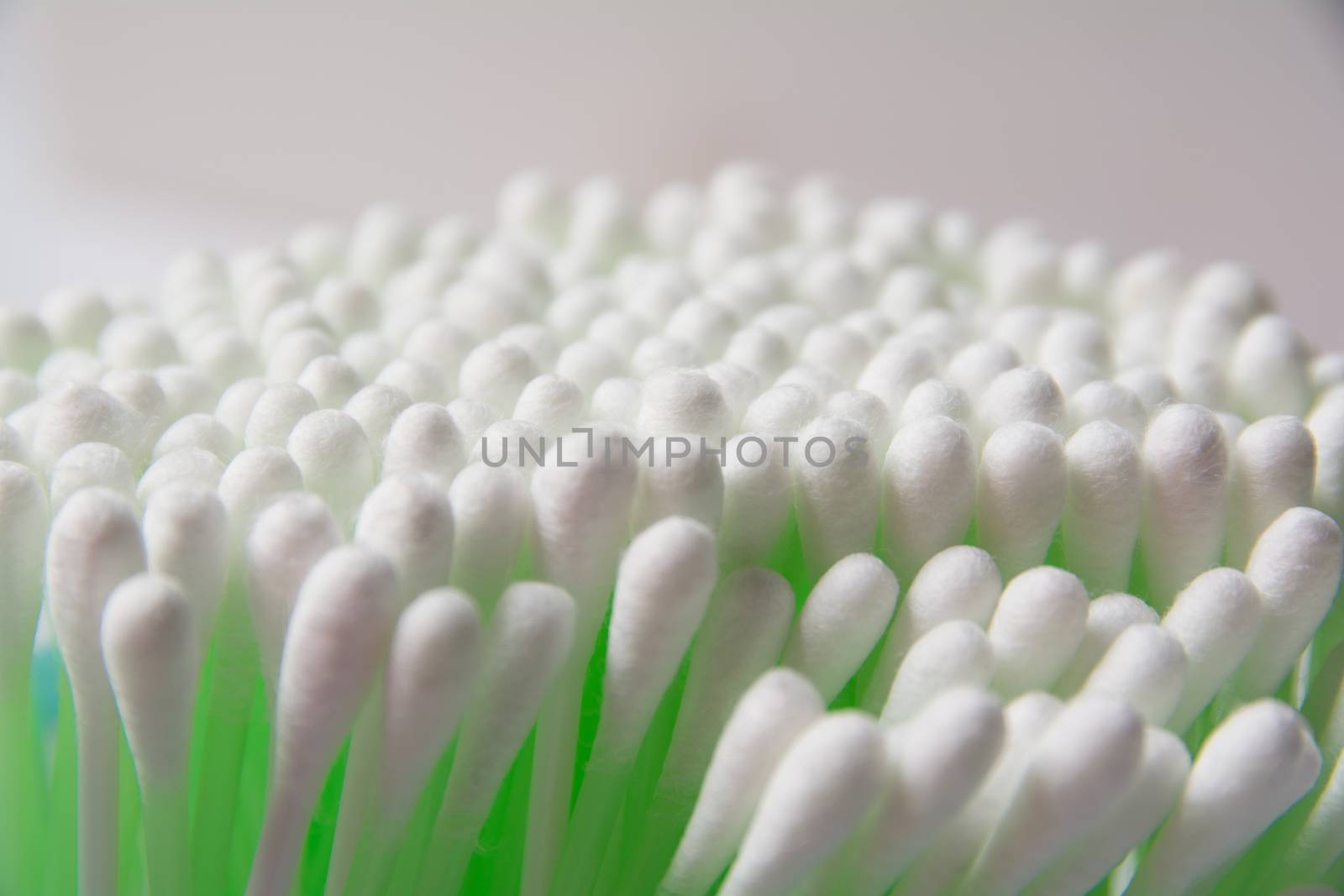 Green cotton swab bud over the grey background. Group of green plastic cotton swabs.