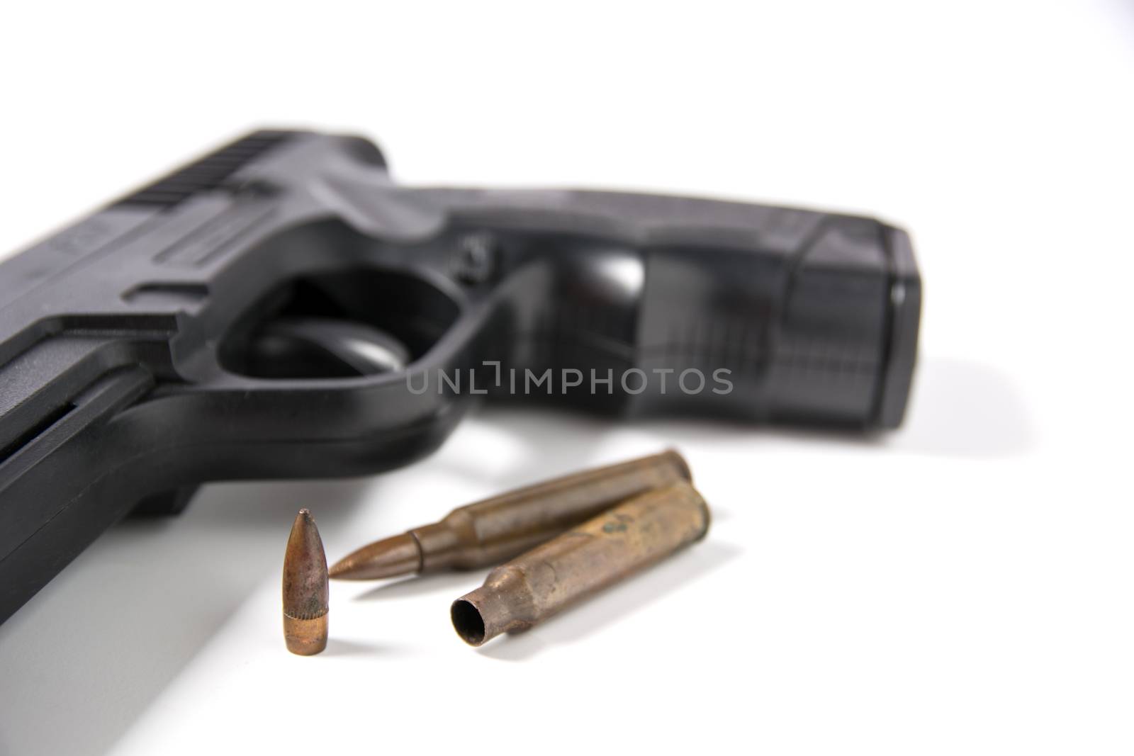 Hand gun sitting with m-16 bullets isolated on white background.