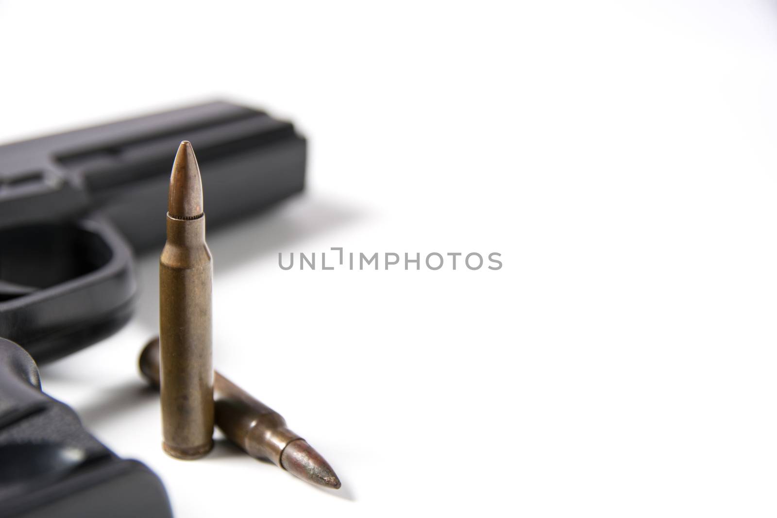 Hand gun sitting with m-16 bullets isolated on white background.