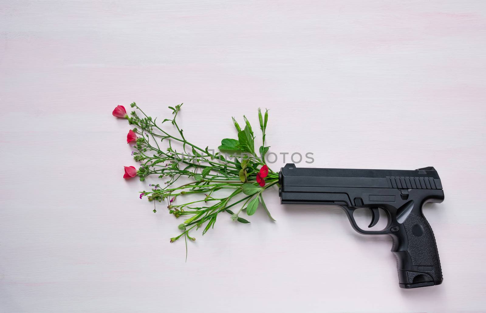 Handgun on wooden background with flowers.War and peace full with hand gun.