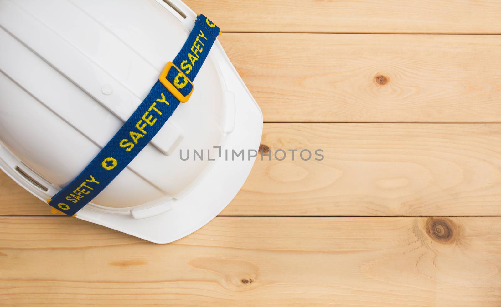 White plastic safety helmet on wooden desk with copy space. by kirisa99