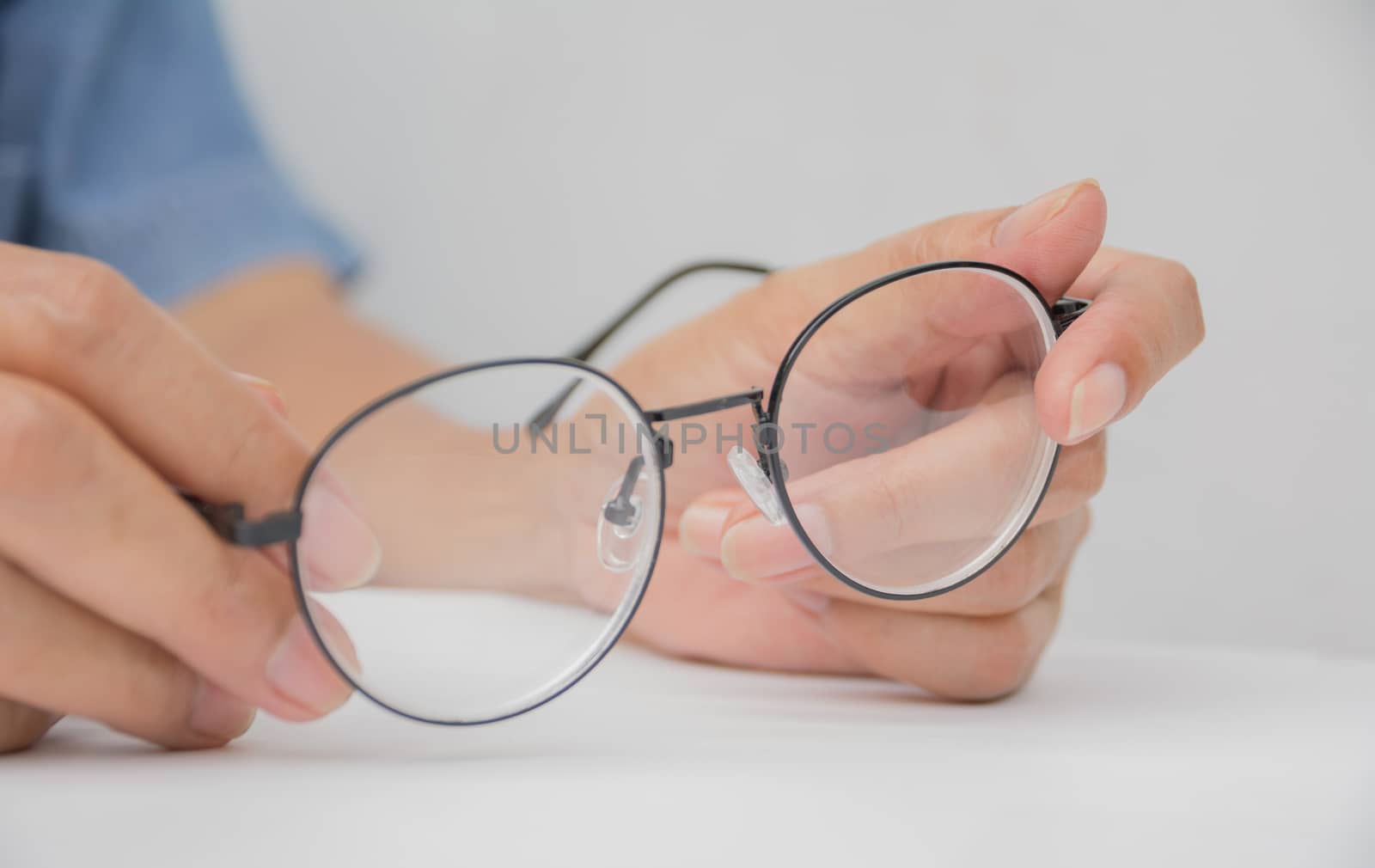 woman hand holding Eye Glasses on white table and white background.