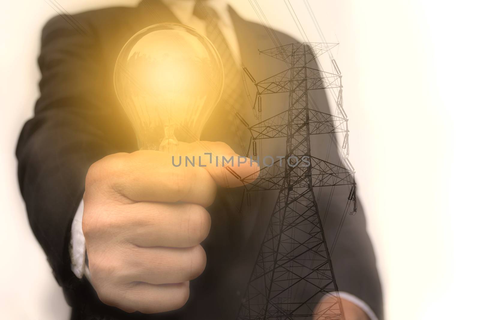 Double exposure close up of businessman hands holding glass light bulb with electricity post.