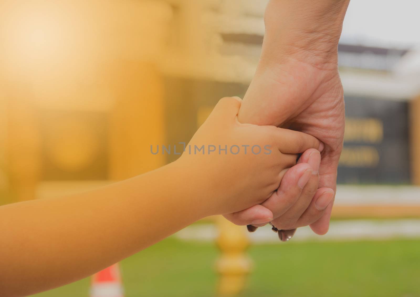 Close up of mother and a child hands at the sunset. Mother holding a hand of son in summer day outdoors.