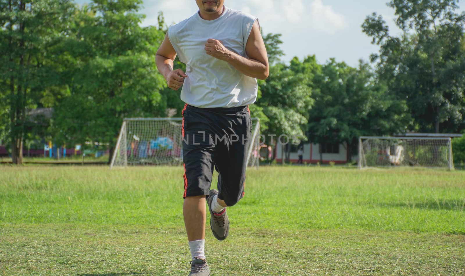 Man running in grass field for exercise. Healthy lifestyle. Handsome man running on grass field in morning 