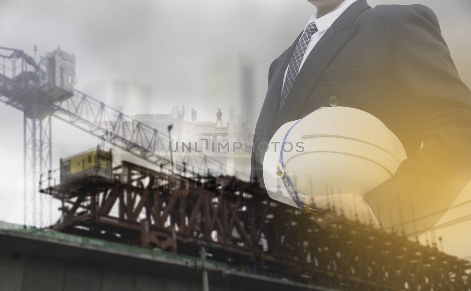 Businessman or safety officer holding white helmet with the building is background in construction site.