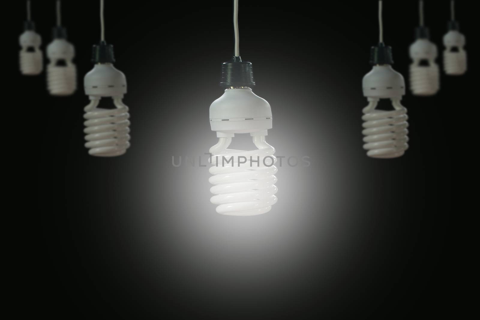 Hanging light bulbs with glowing one on dark background. Idea an by kirisa99