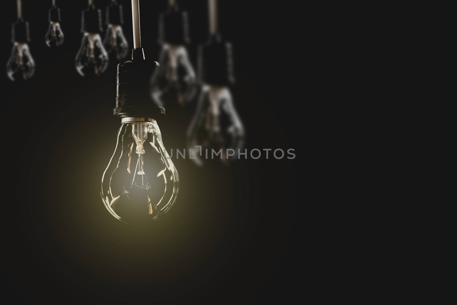 Hanging light bulbs with glowing one on dark background. Idea an by kirisa99