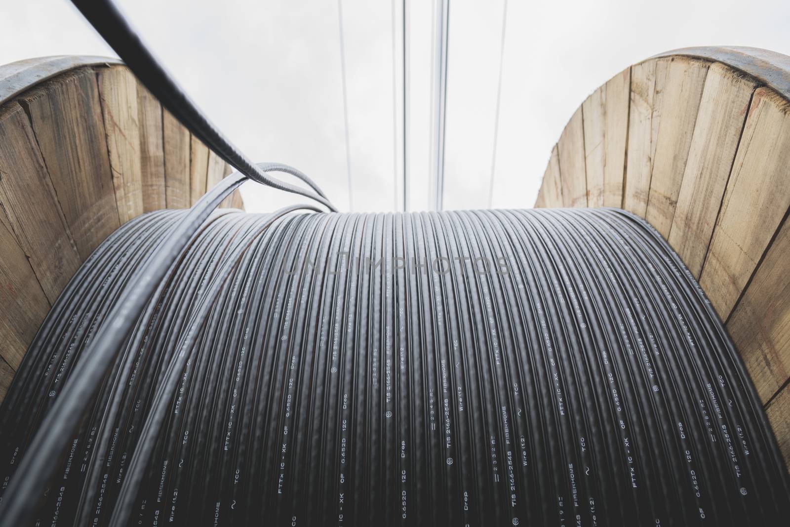 black wire  electric cable with wooden coil of electric cable under the sky.