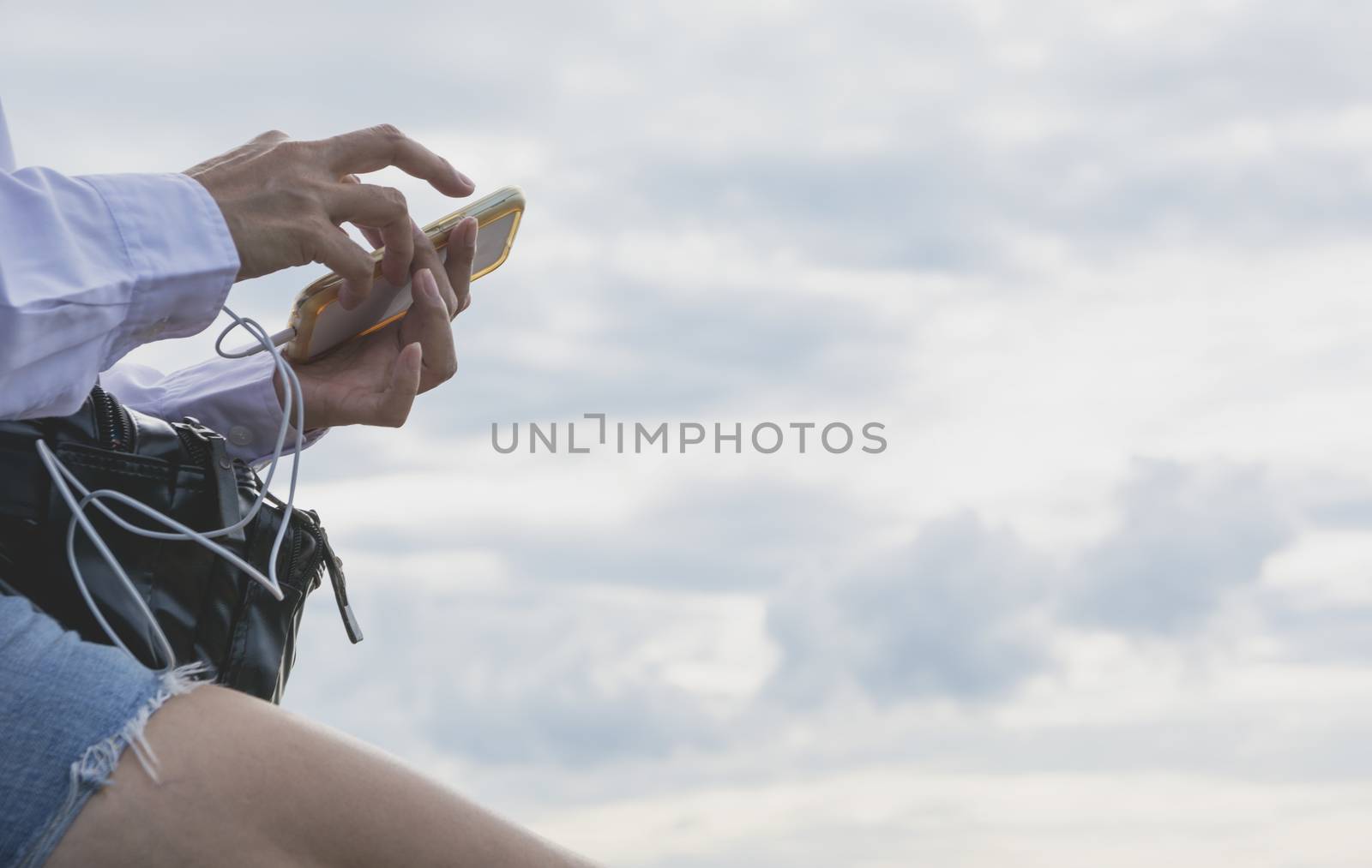 Woman using smartphone, personal chat, and social media under the sky.