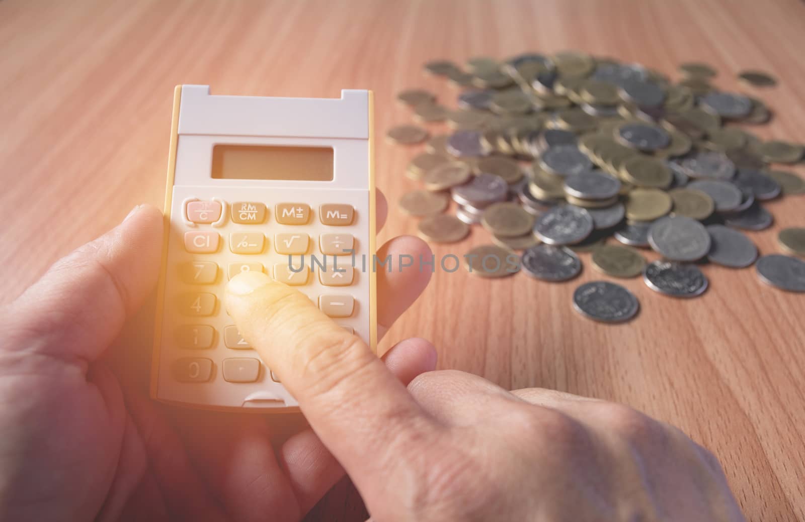 Hand of man are pressing the calculator with coins on the wooden by kirisa99