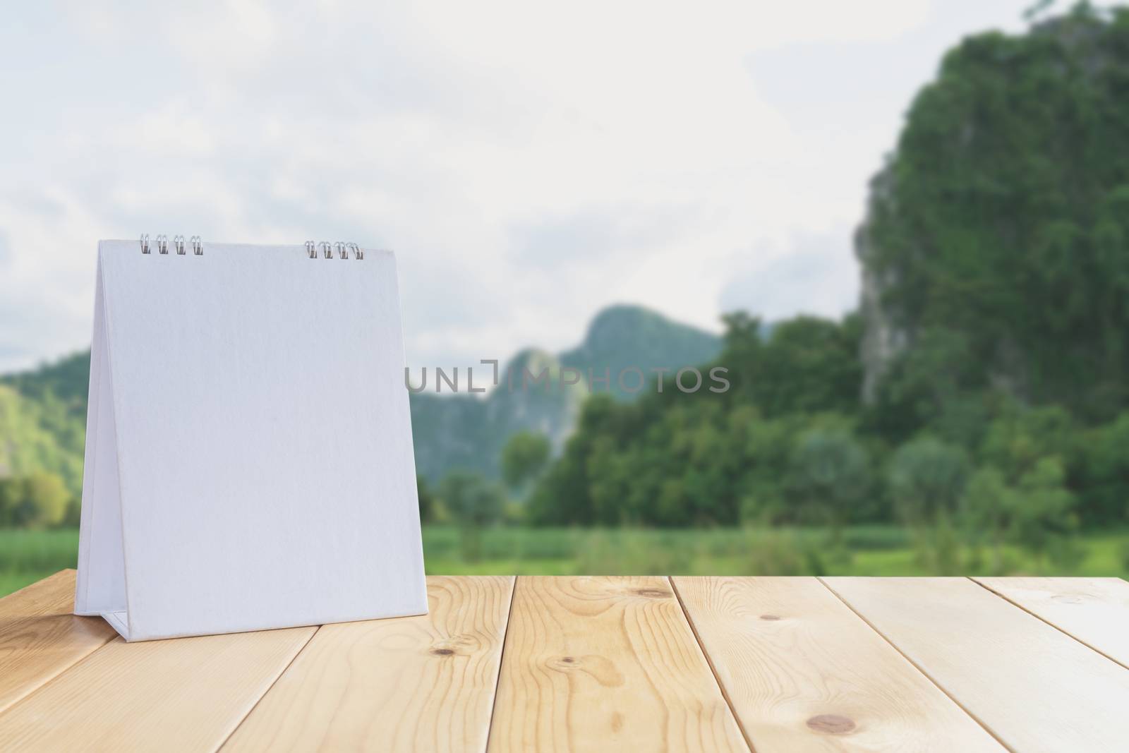 White calendar on wood table on nature background and copy space mock up.