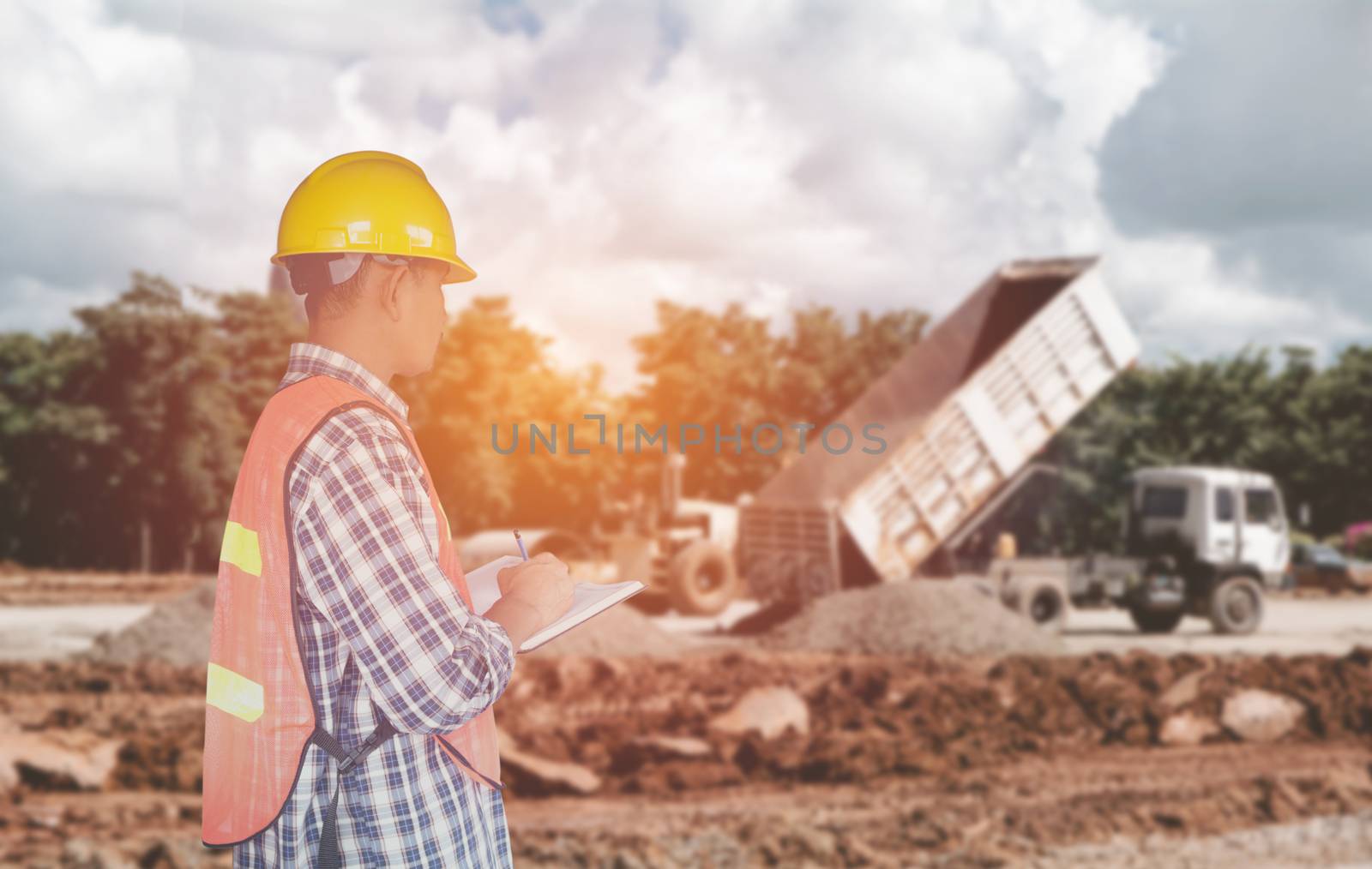 Engineer or safety officer wear yellow helmet with the building is background in construction site.