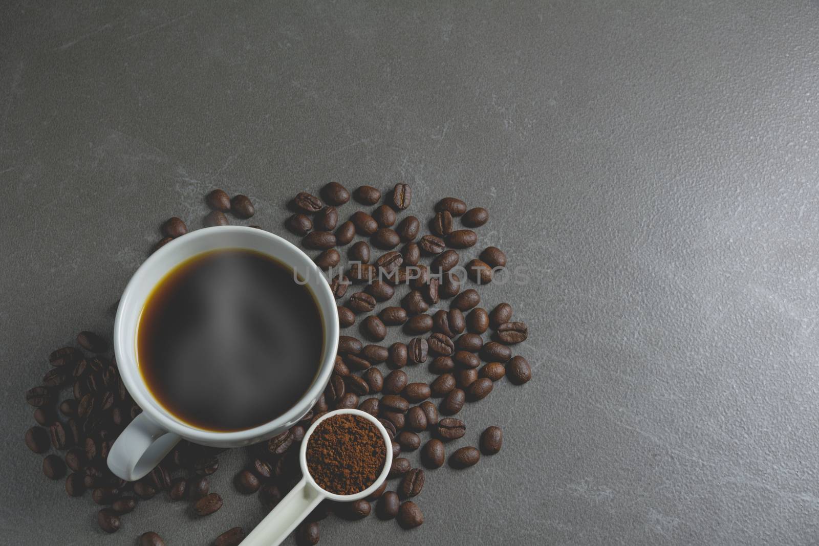 Coffee beans and coffee in white cup on black table.