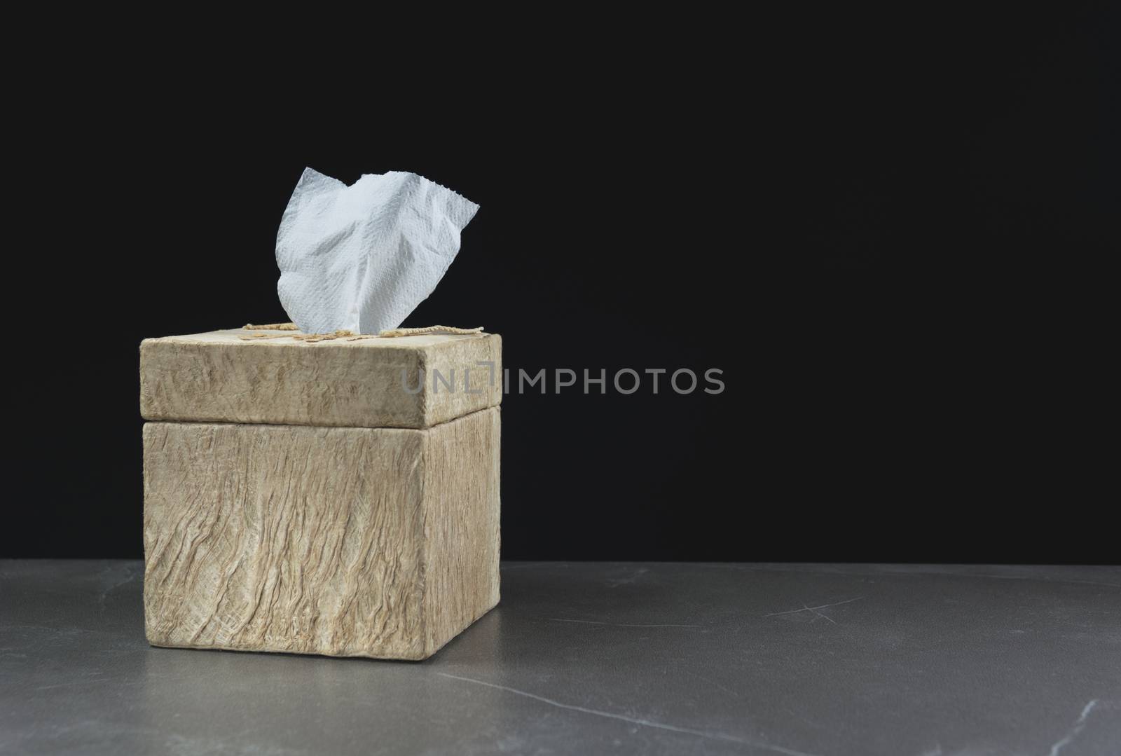 Close-up image one of toilet papers roll in box on the table with dark background.