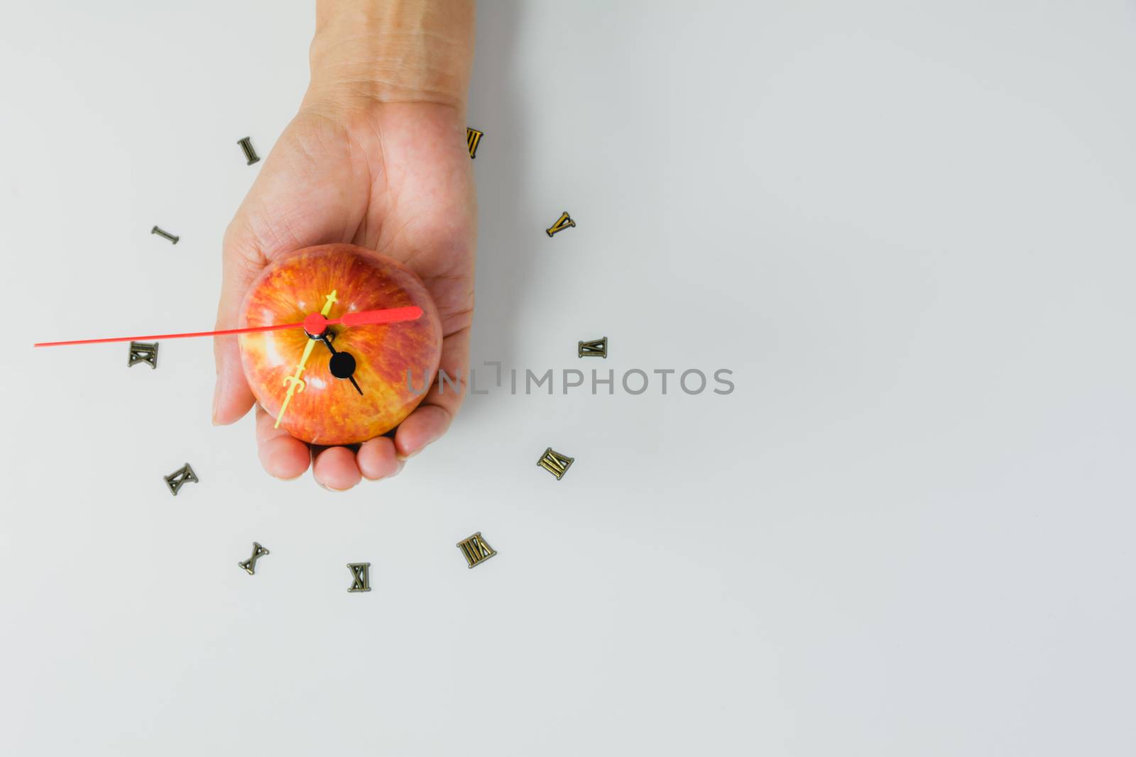 Hand holding apple with number of clock, apple shape clock on white background with copy space. 