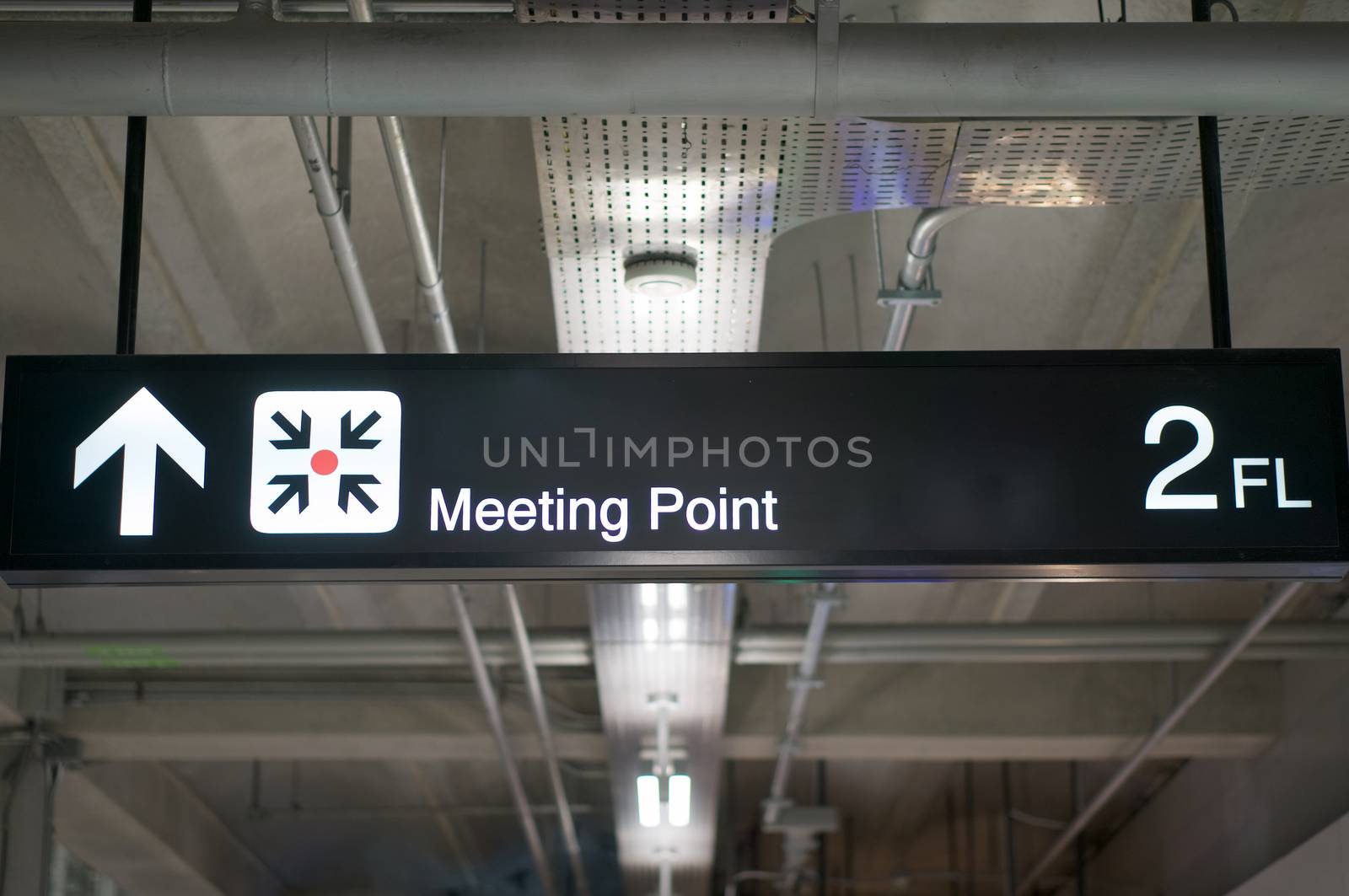 Meeting point information board sign with white character on black background at international airport terminal.