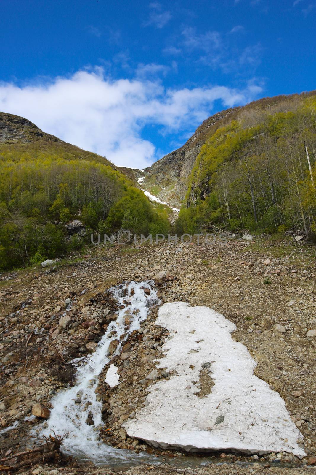 Mountain stream of melting snow water at sunny day