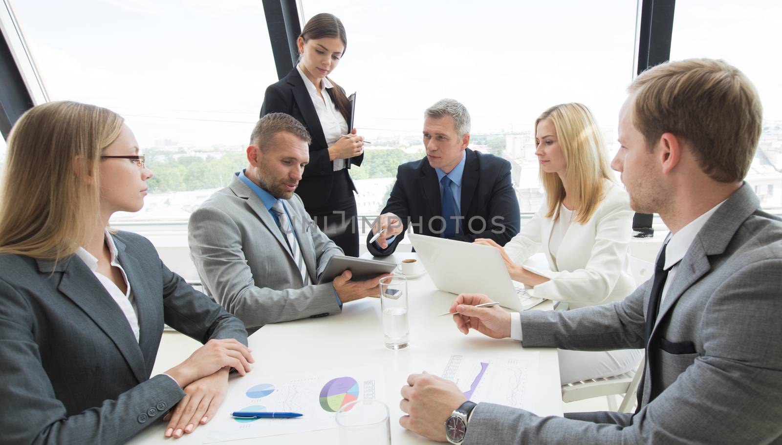 Business person group in formalwear discuss documents at meeting in modern office