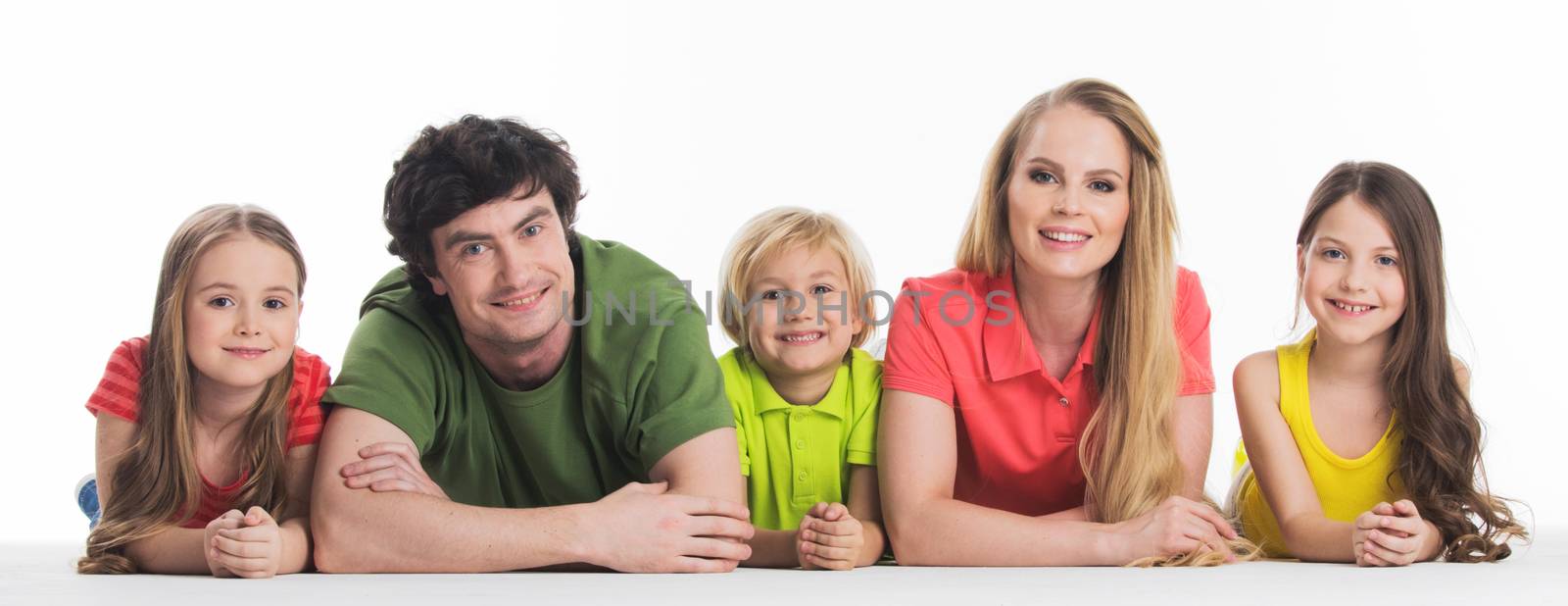 Happy smiling family of two parents and three children lying on the floor studio isolated on white background