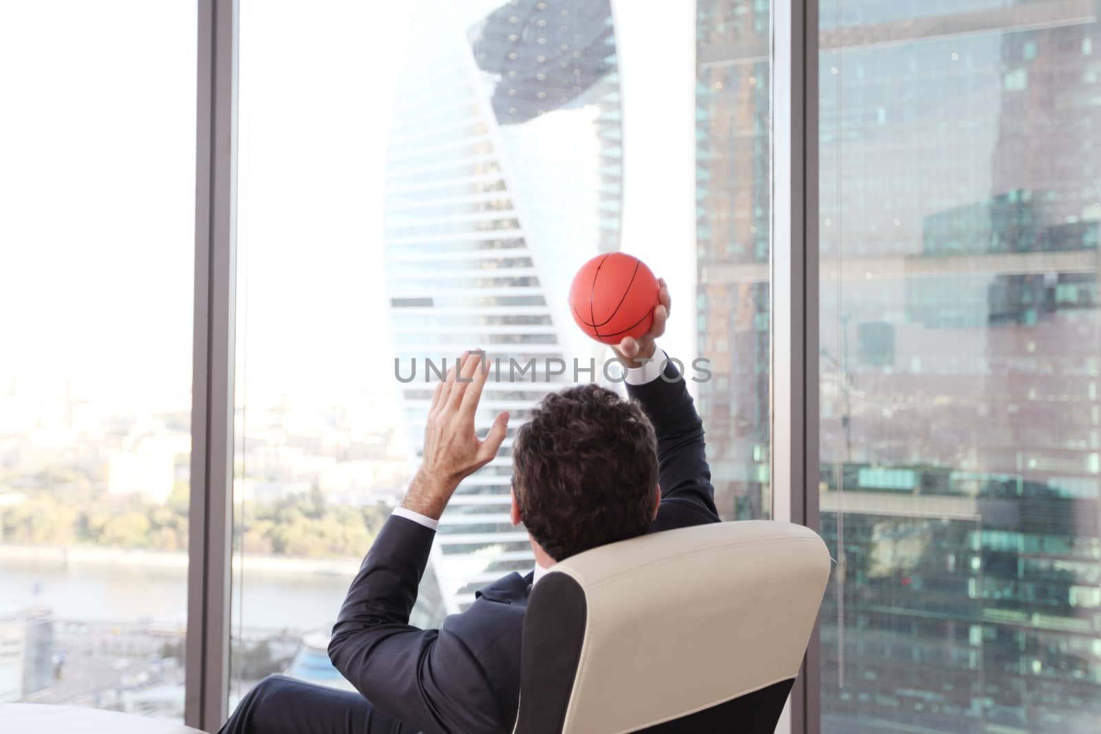 Business man playing with a basketball at the office