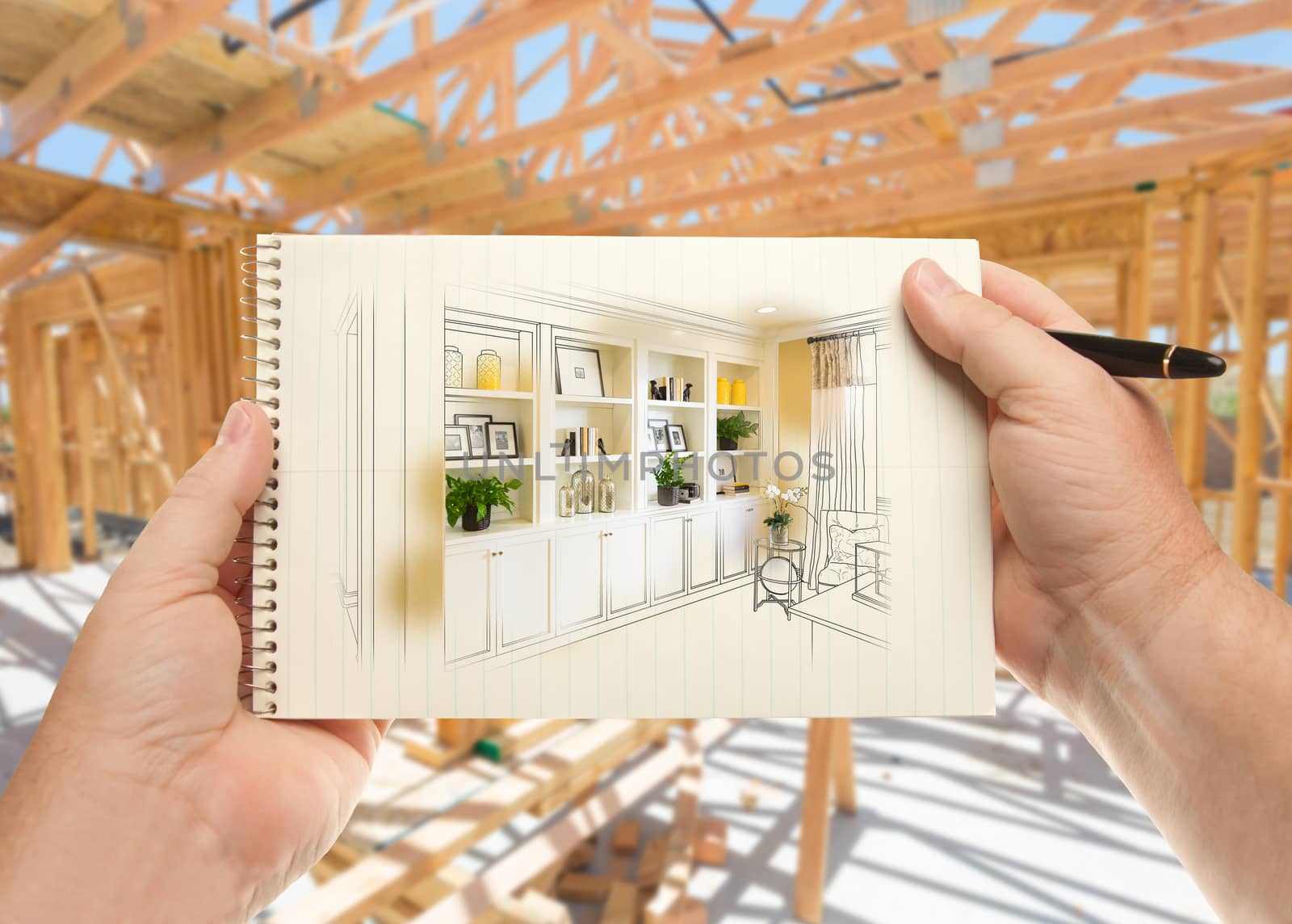 Hands Holding Pen and Pad of Paper with Built-in Shelves and Cabinets Inside House Construction Framing. by Feverpitched