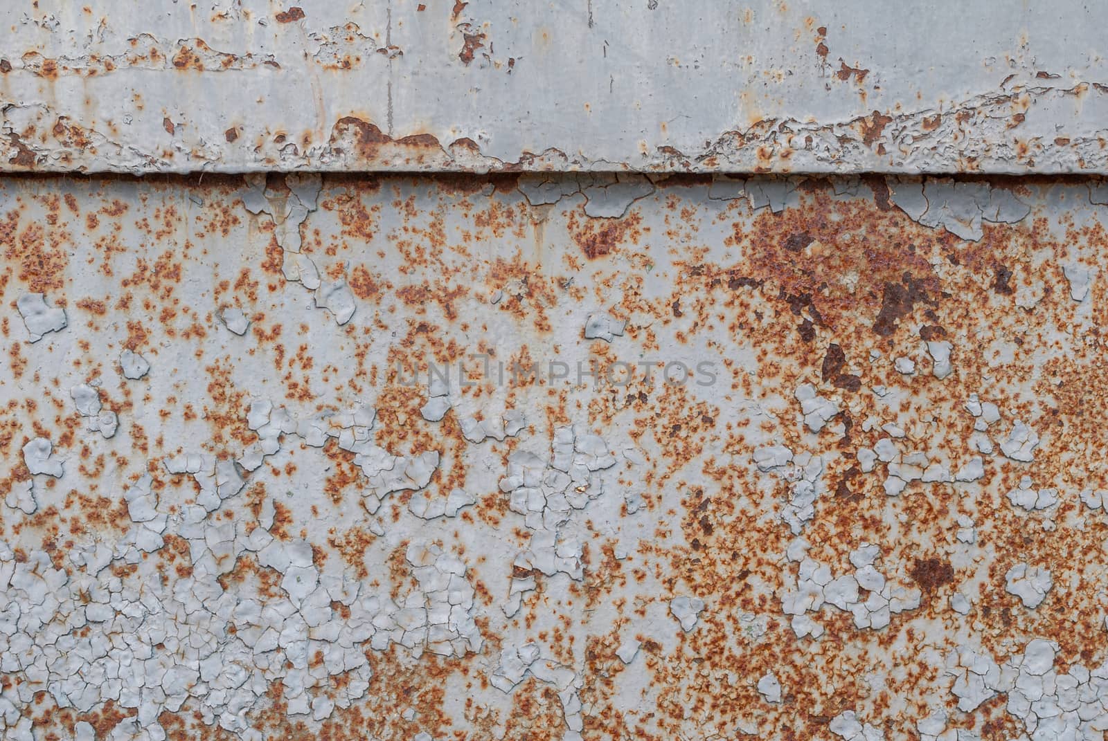 fragment of an iron surface is covered with grey color paint, which has long been under the influence of different climatic conditions