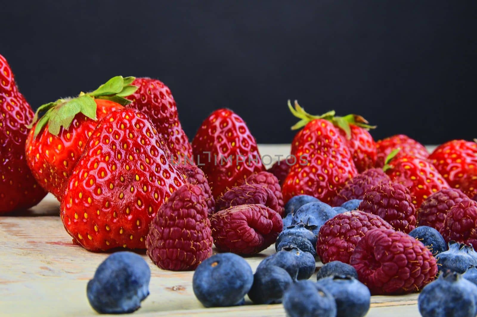 Healthy mixed fruit and ingredients with strawberry, raspberry, blueberry. Berries on rustic white wooden background. Free space for text. Copy space for banner.