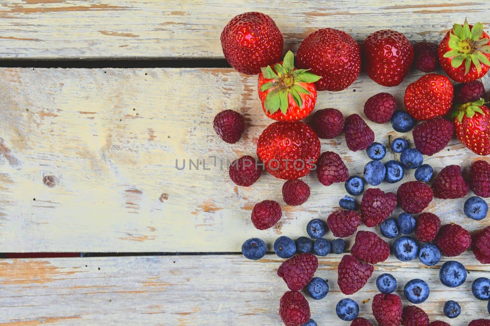 Healthy mixed fruit and ingredients with strawberry, raspberry, blueberry from top view. Berries on rustic white wooden background. Flat design. Free space for text. Copy space for banner.