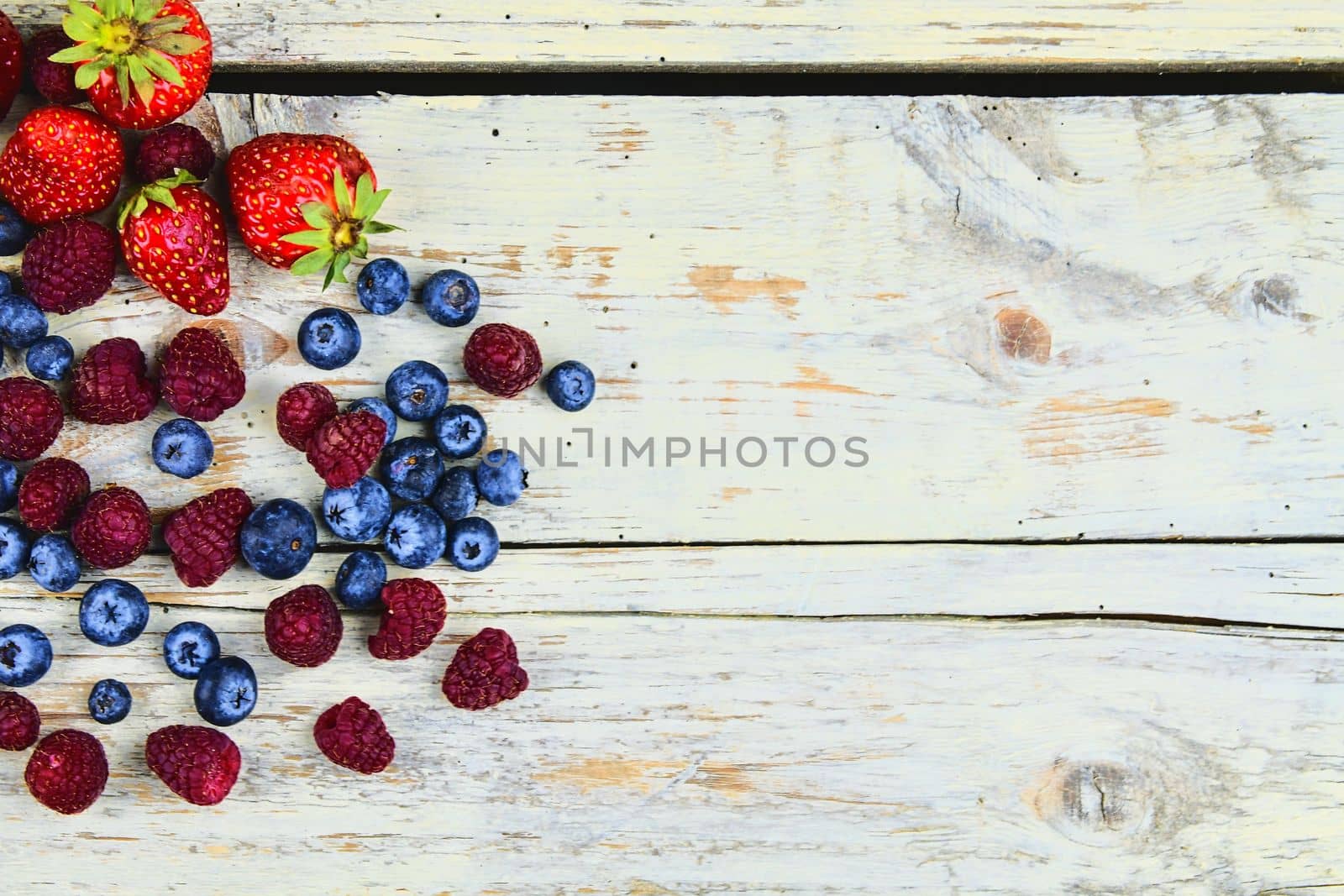 Healthy mixed fruit and ingredients with strawberry, raspberry, blueberry from top view. Berries on rustic white wooden background. Flat design. Free space for text. Copy space for banner by roman_nerud