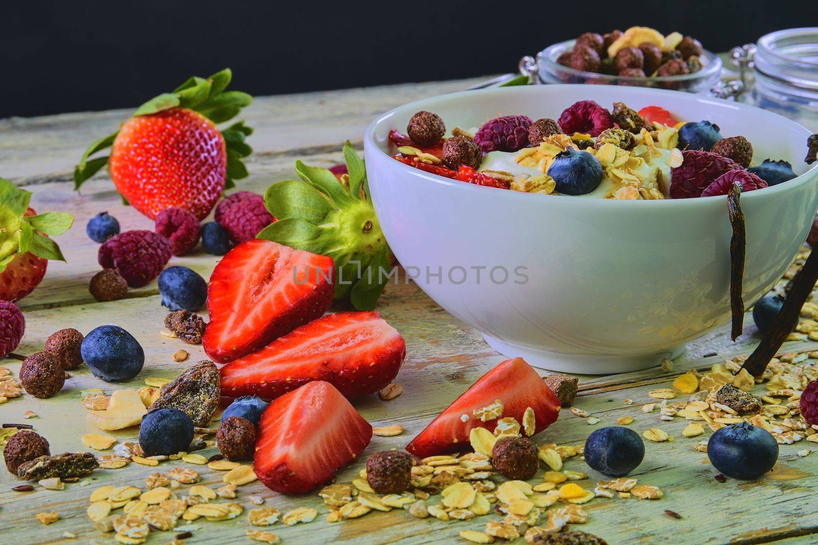 Healthy breakfast, cereal with yoghurt, strawberries, blueberries, raspberries and muesli on wooden rustic background.  Concept of: fitness, diet, wellness and breakfasts.