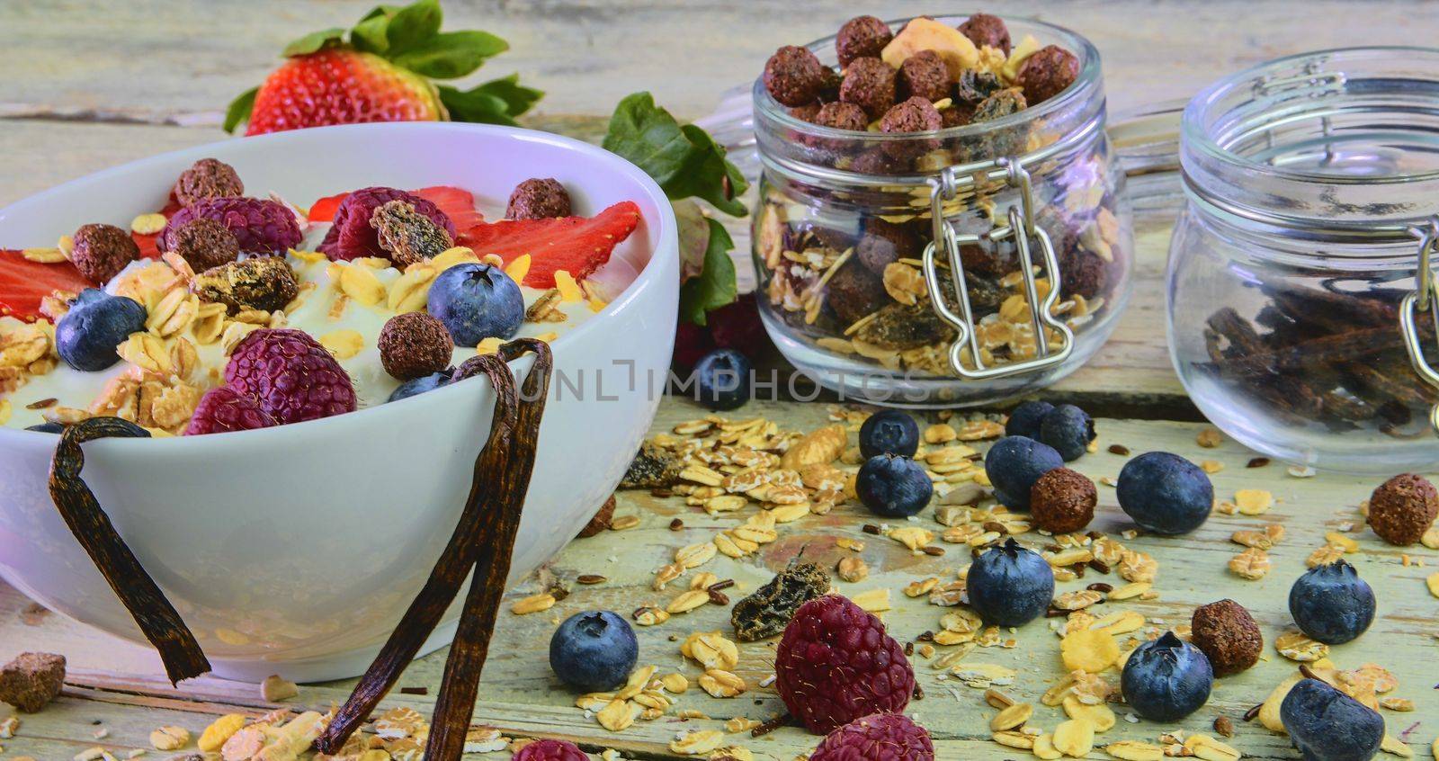 Healthy breakfast, cereal with yoghurt, strawberries, blueberries, raspberries and muesli on wooden rustic background.  Concept of: fitness, diet, wellness and breakfasts by roman_nerud