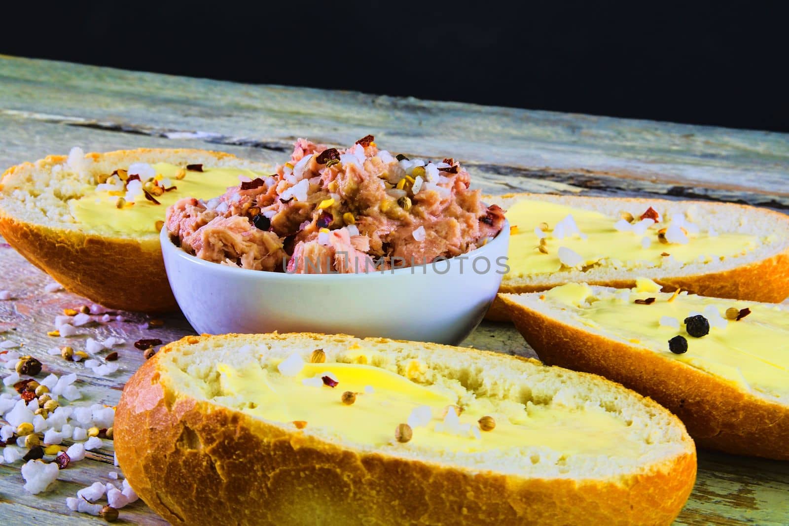 Slices of baguettes with butter and  fresh tuna with spices on wooden background by roman_nerud