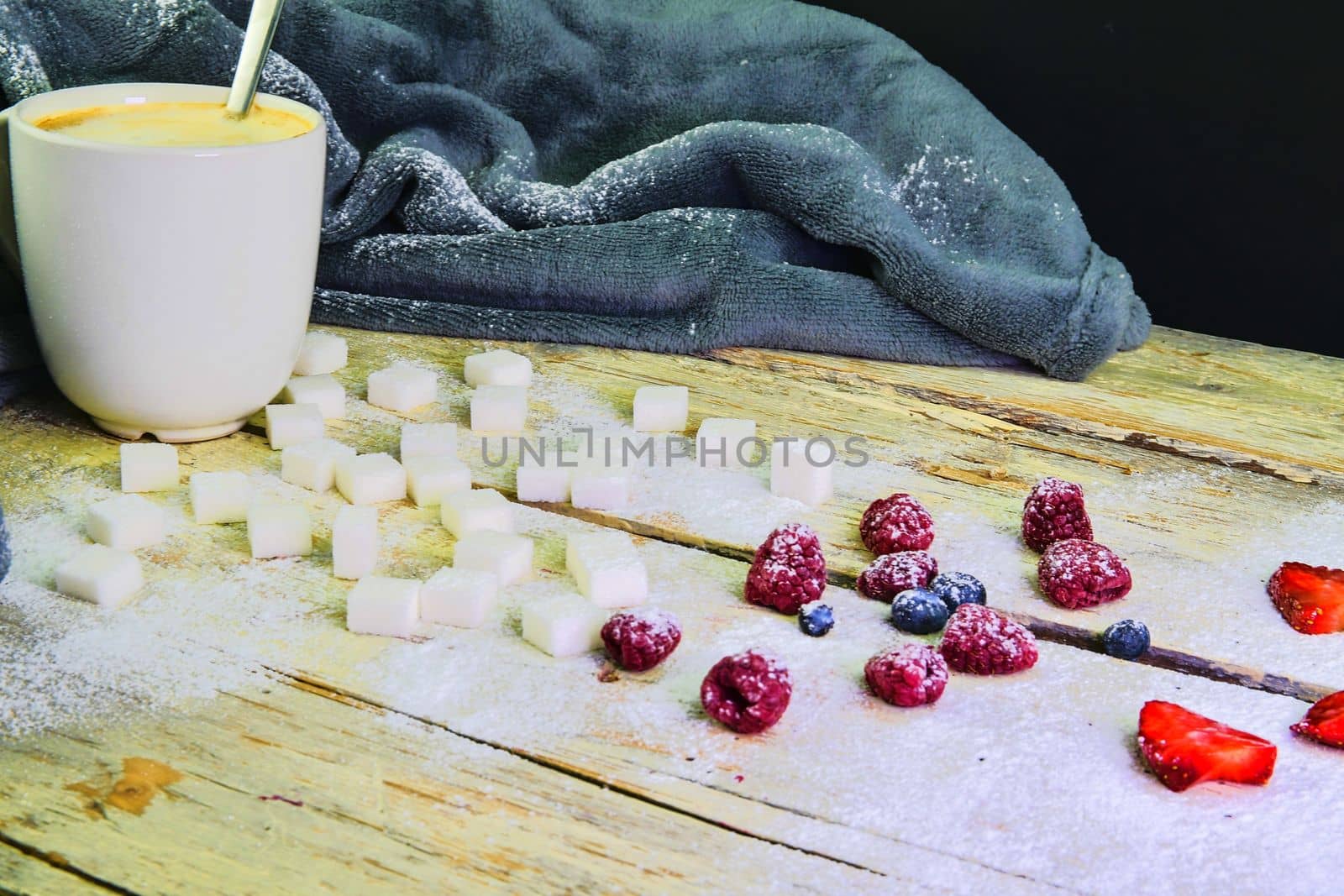Cup of coffee, sugar cubes, blueberries and strawberries on wooden background. Winter or Valentines day concept by roman_nerud