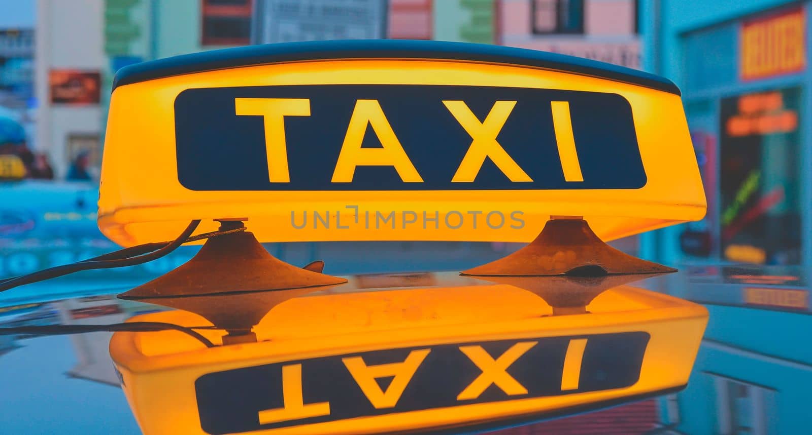 Lit taxi sign on roof of taxi car in the city.