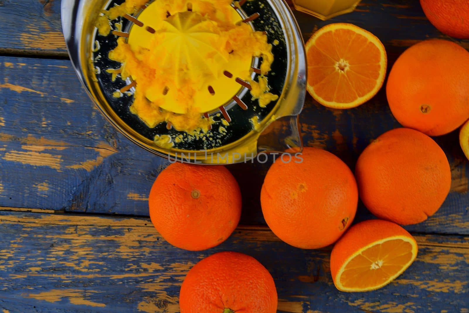 Tangerines, oranges, a glass of orange juice and manual citrus squezeer on blue wooden background. Oranges cut in half. Top view, flat design by roman_nerud