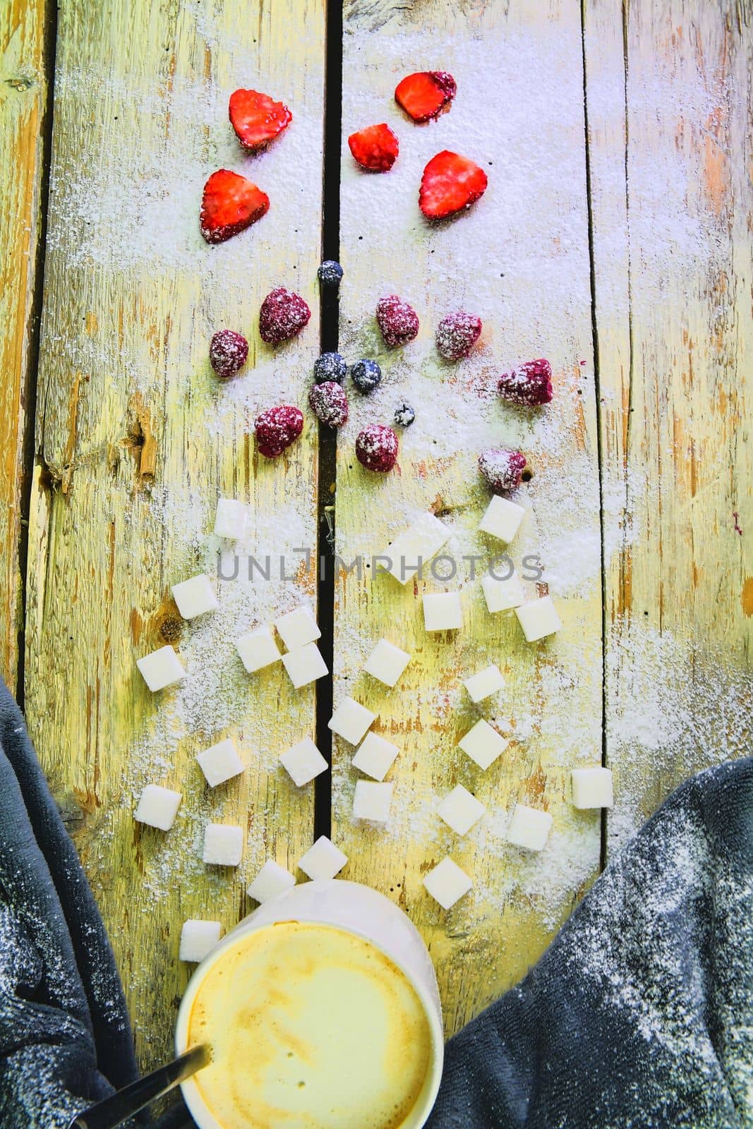 Cup of coffee, sugar cubes, blueberries and strawberries on wooden background. Winter or Valentines day concept. Flat design, flat lay, top view.
