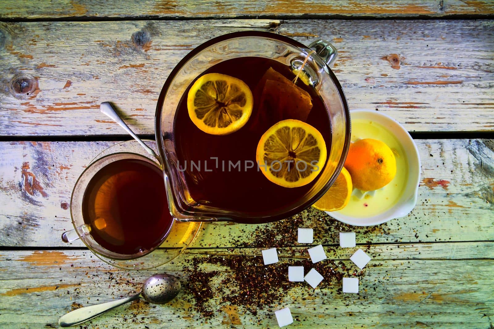 Black tea, a cup of black tea, manual squeezer with lemons. A jug of black tea and cubes of sugar. Top view, flat design by roman_nerud