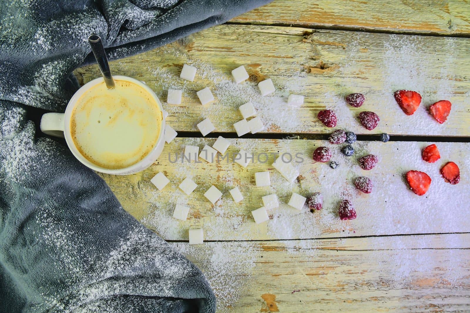 Cup of coffee, sugar cubes, blueberries and strawberries on wooden background. Winter or Valentines day concept. Flat design, flat lay, top view.