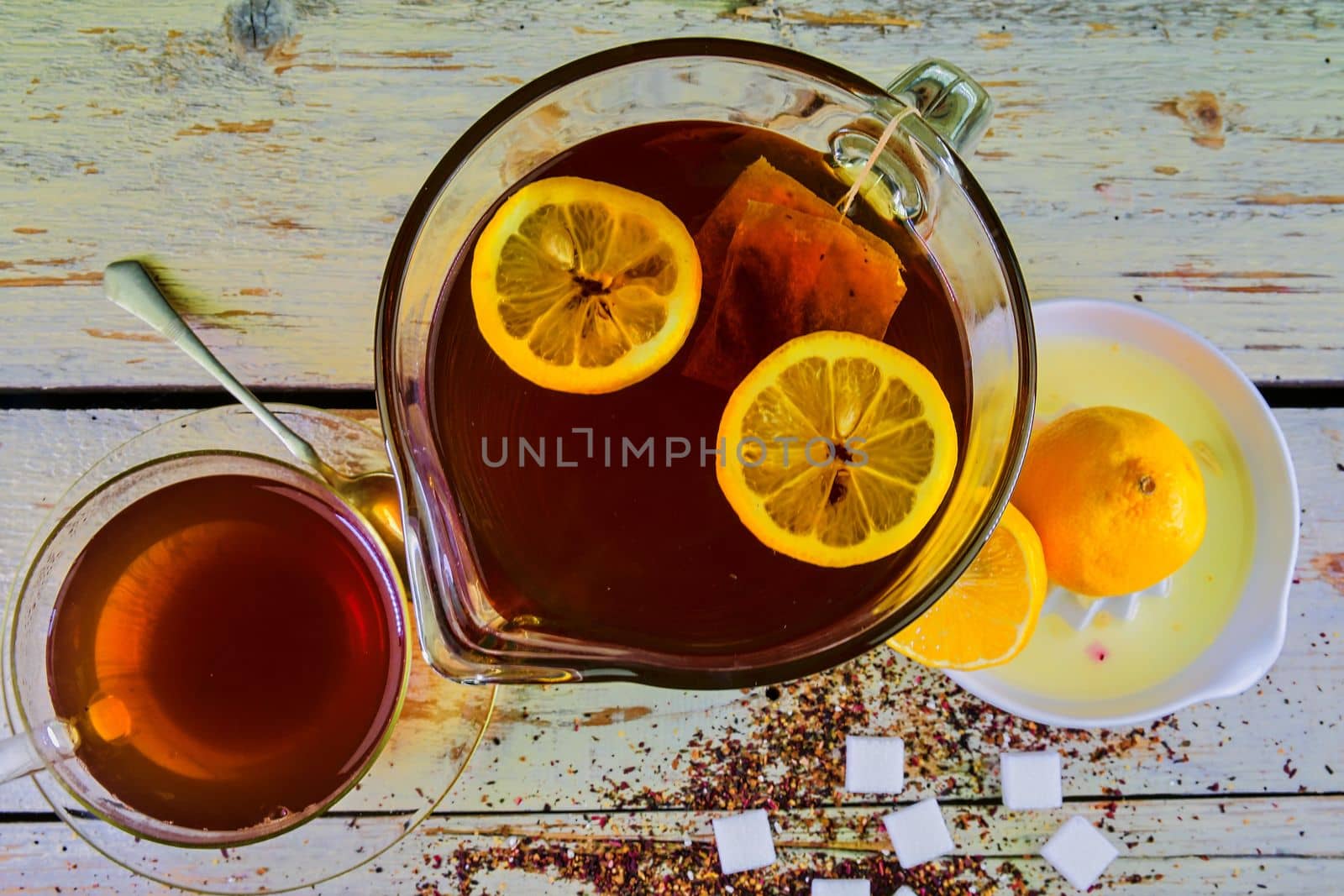 Black tea, a cup of black tea, manual squeezer with lemons. A jug of black tea and cubes of sugar. Top view, flat design by roman_nerud