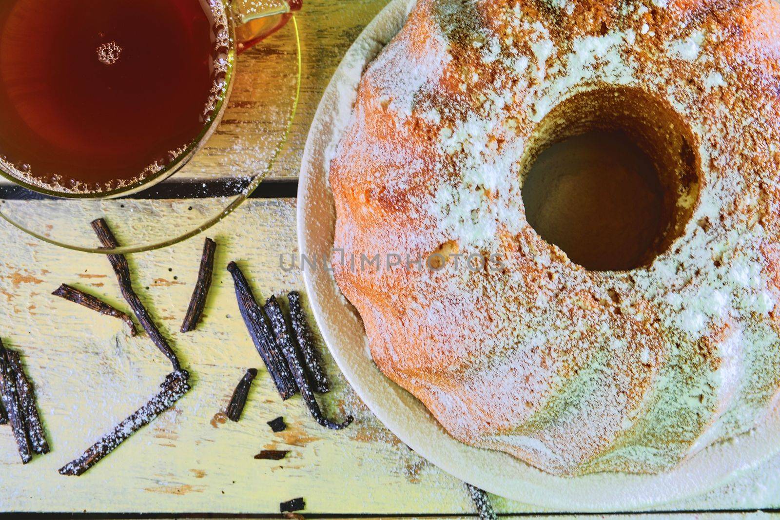 Old fashioned sand cake with cup of black tea and pieces of vanilla on wooden background. Egg-yolk sponge cake on rustic white background. Top view. Flat design.